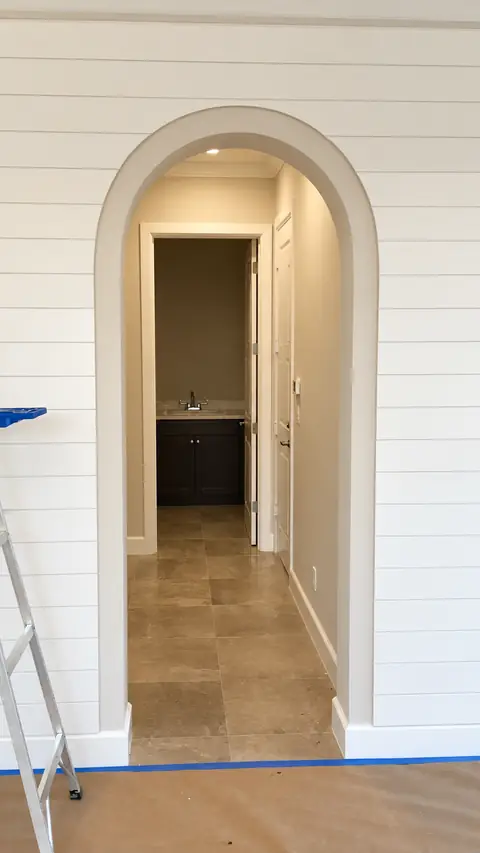 Arched doorway set in a white shiplap wall