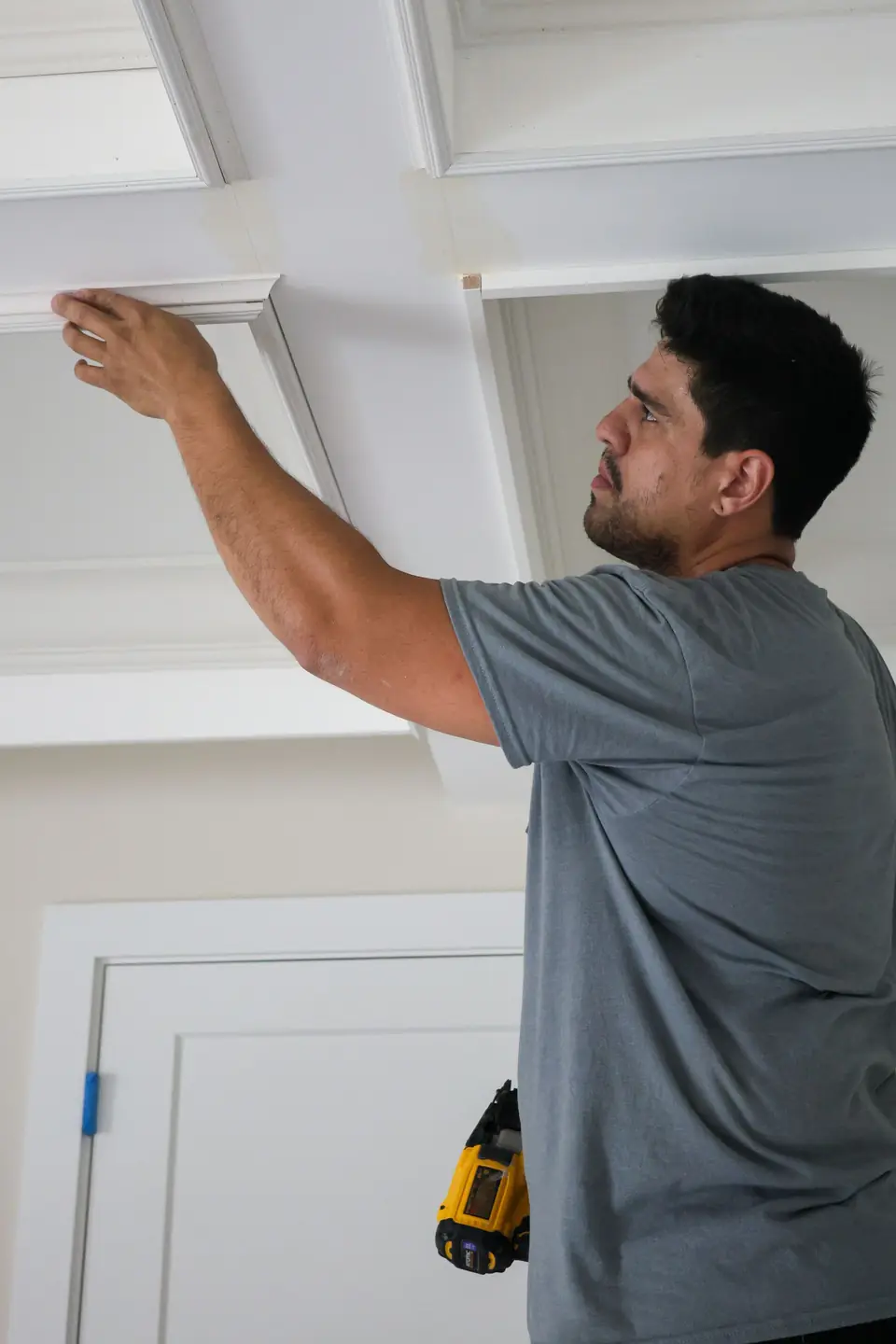 Carpentry Squad carpenter fastening trim on a coffered ceiling