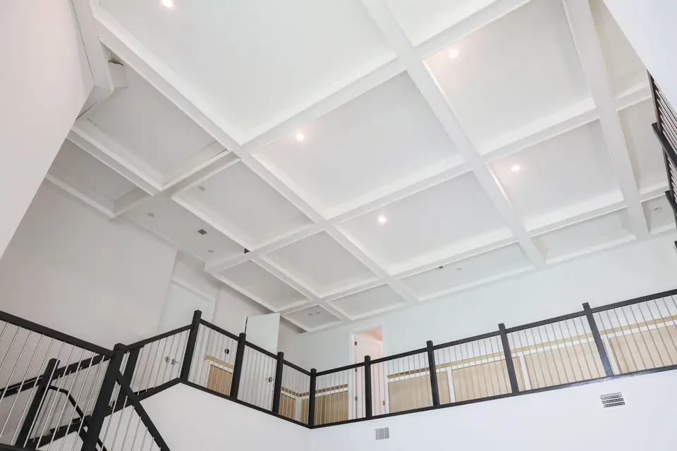 Wide view of a white coffered ceiling over an upstairs landing